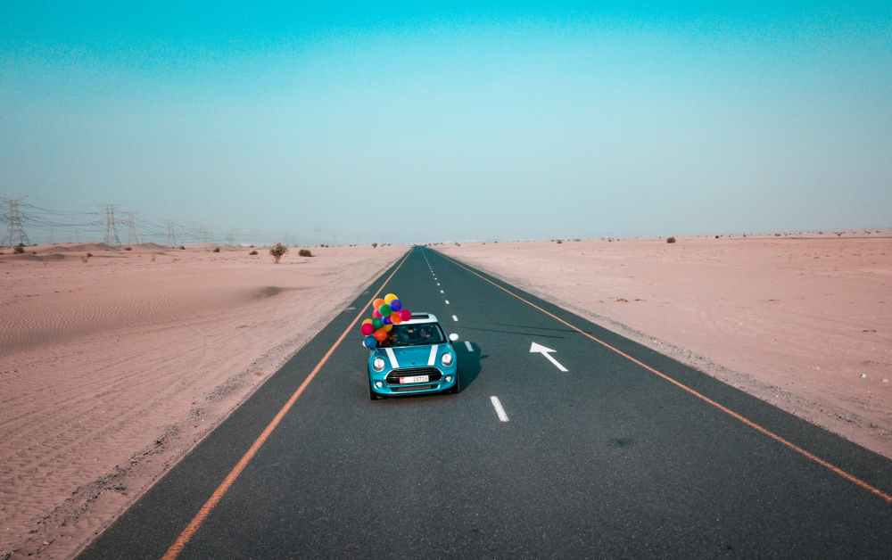 blue and white mini cooper with balloons running on road